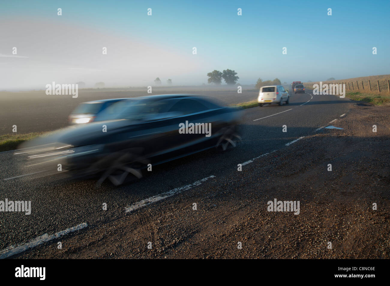Traffic driving in fog and mist on a flat road in Cambrudgeshire, using