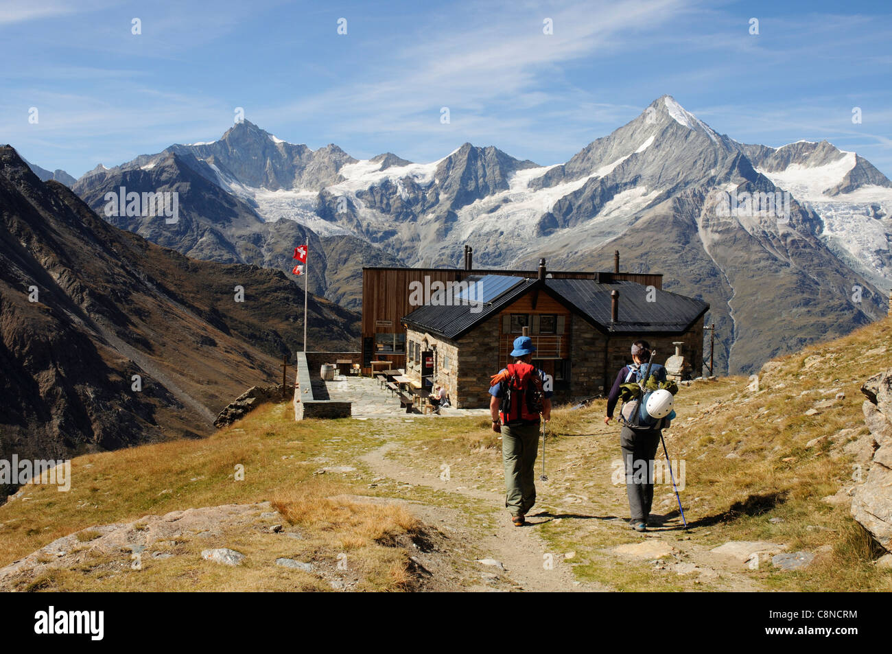 Two people approaching the Tasch hut in the Swiss Alps Stock Photo