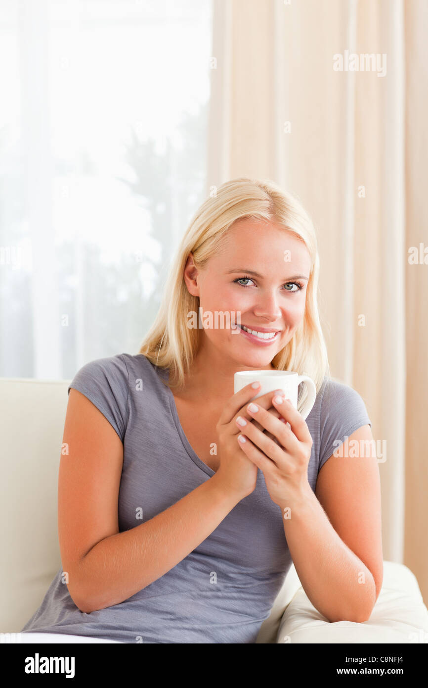 Portrait of a woman sitting on a couch with a cup of tea Stock Photo ...
