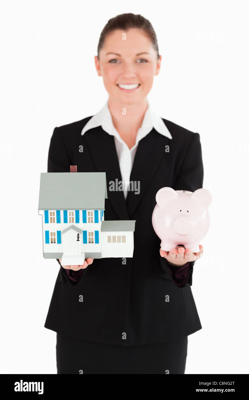 Charming woman in suit holding a piggy bank and a miniature house Stock ...