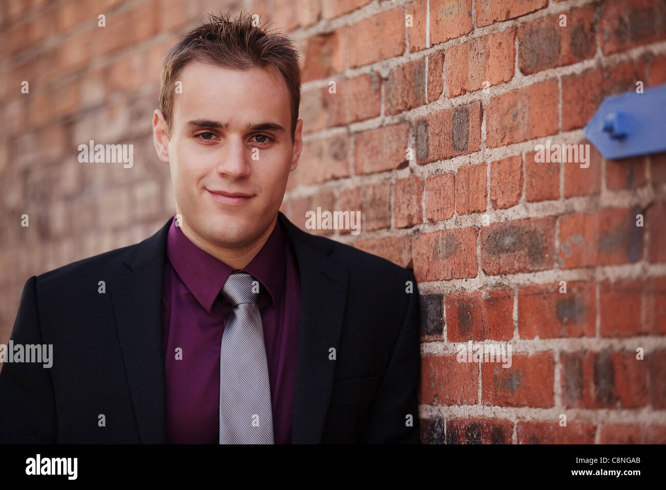 Handsome young businessman leaning against a brick wall Stock Photo - Alamy
