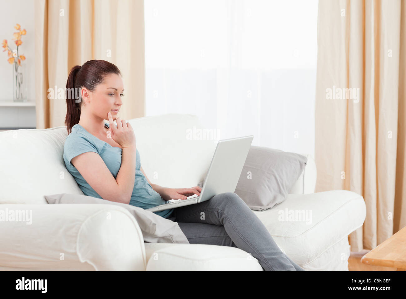Beautiful woman relaxing with her laptop while sitting on a sofa Stock ...