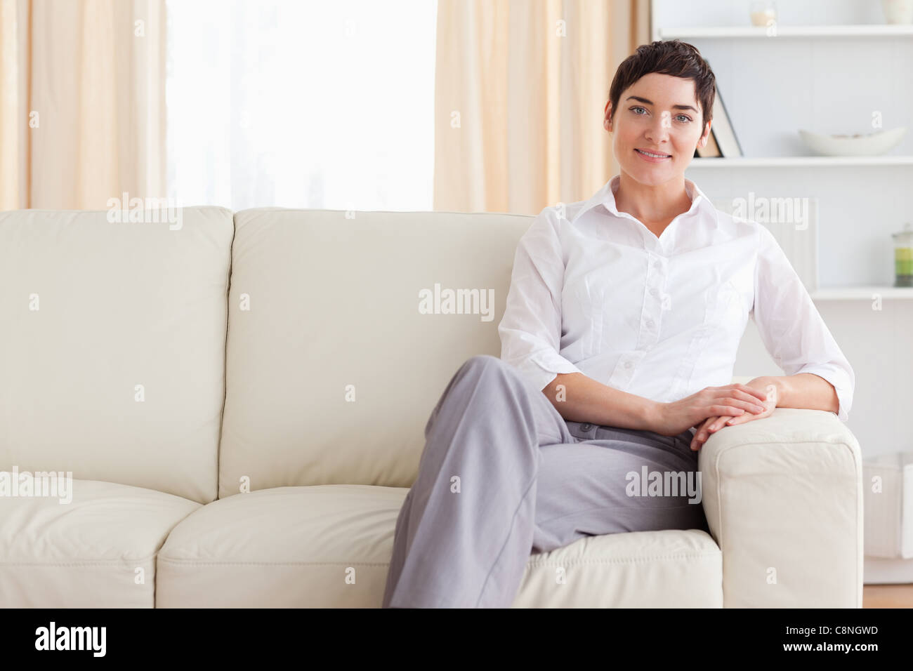 Smiling woman sitting on a sofa Stock Photo - Alamy