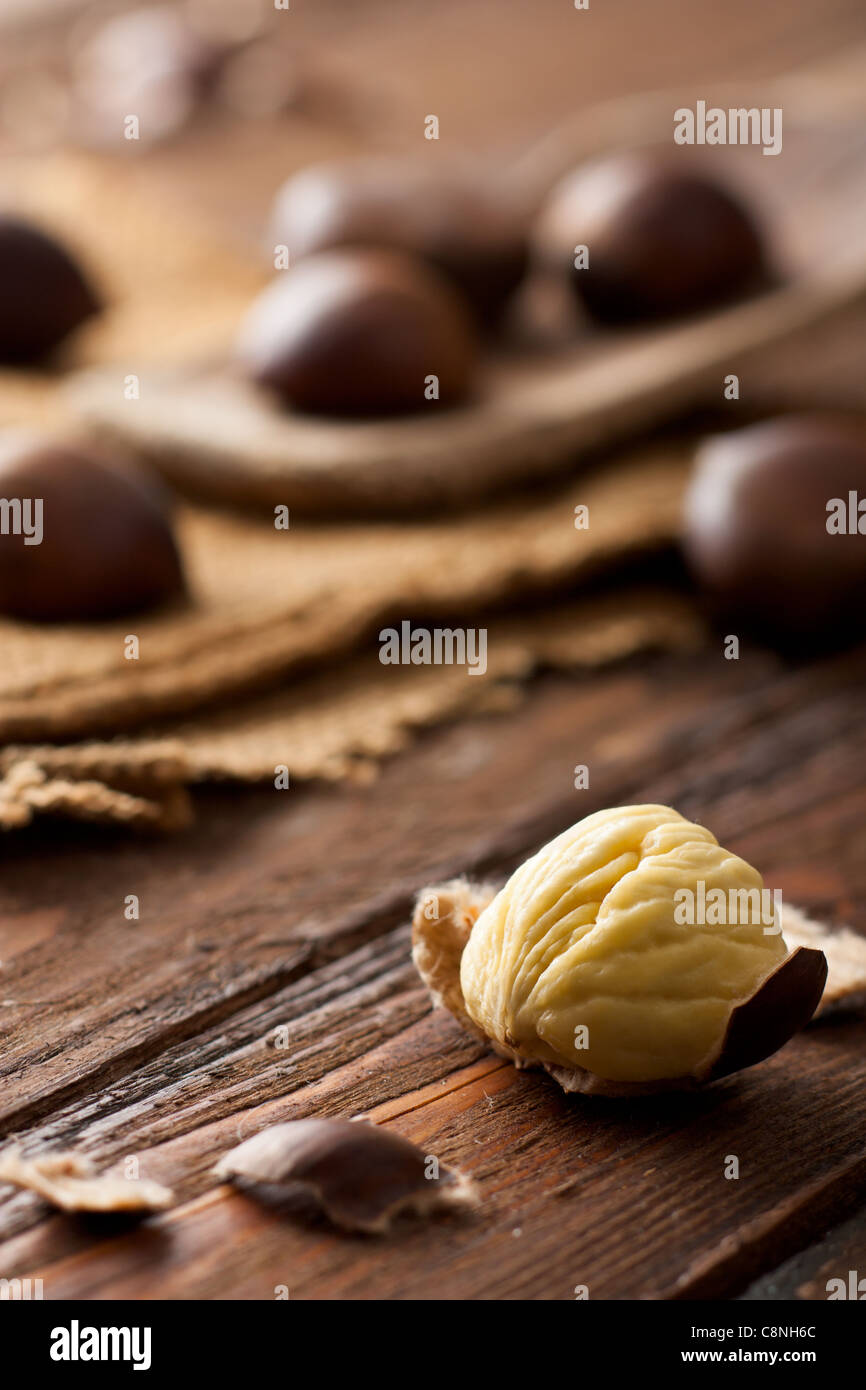 Raw Chestnuts on Wood with Jute and Wooden Spoon Stock Photo