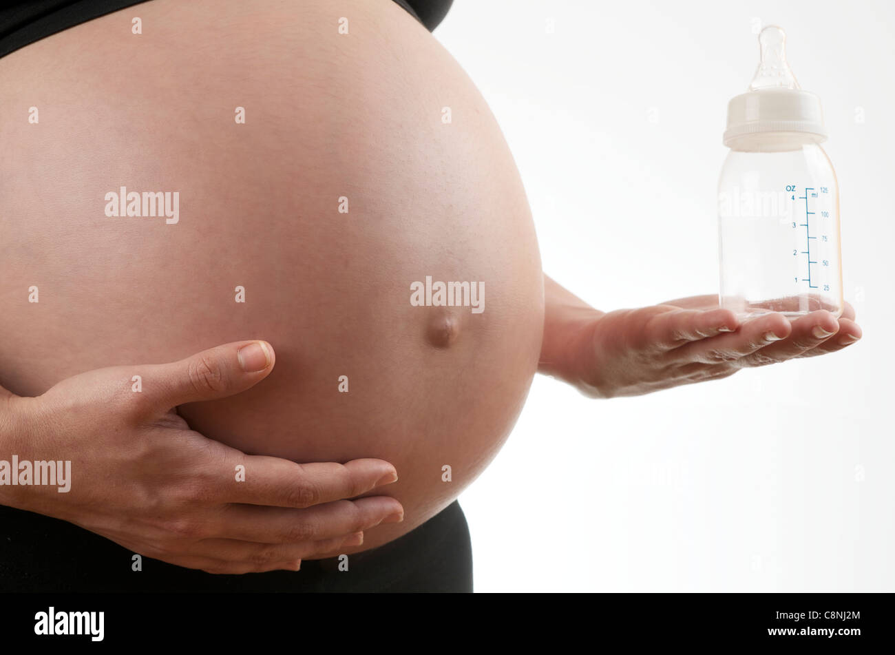 pregnant woman caressing her belly and holding a bottle Stock Photo