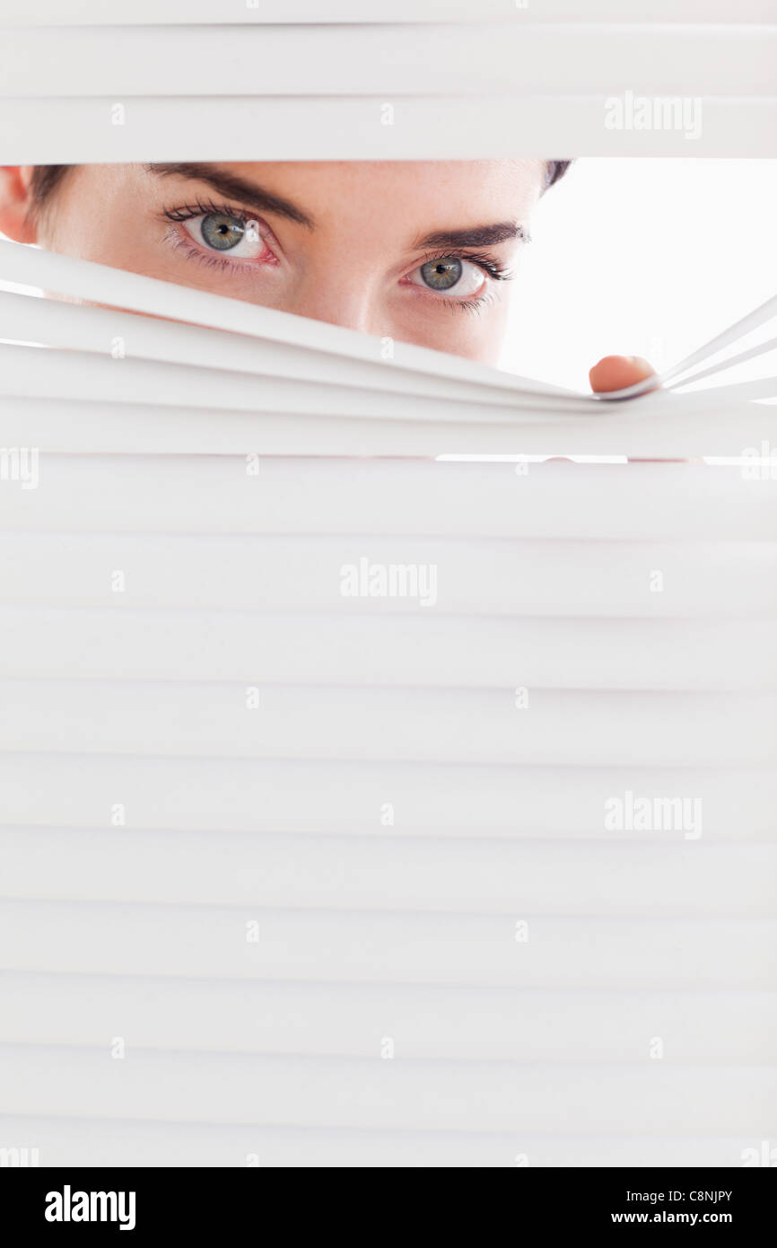 Businesswoman peeking through a venetian blind Stock Photo