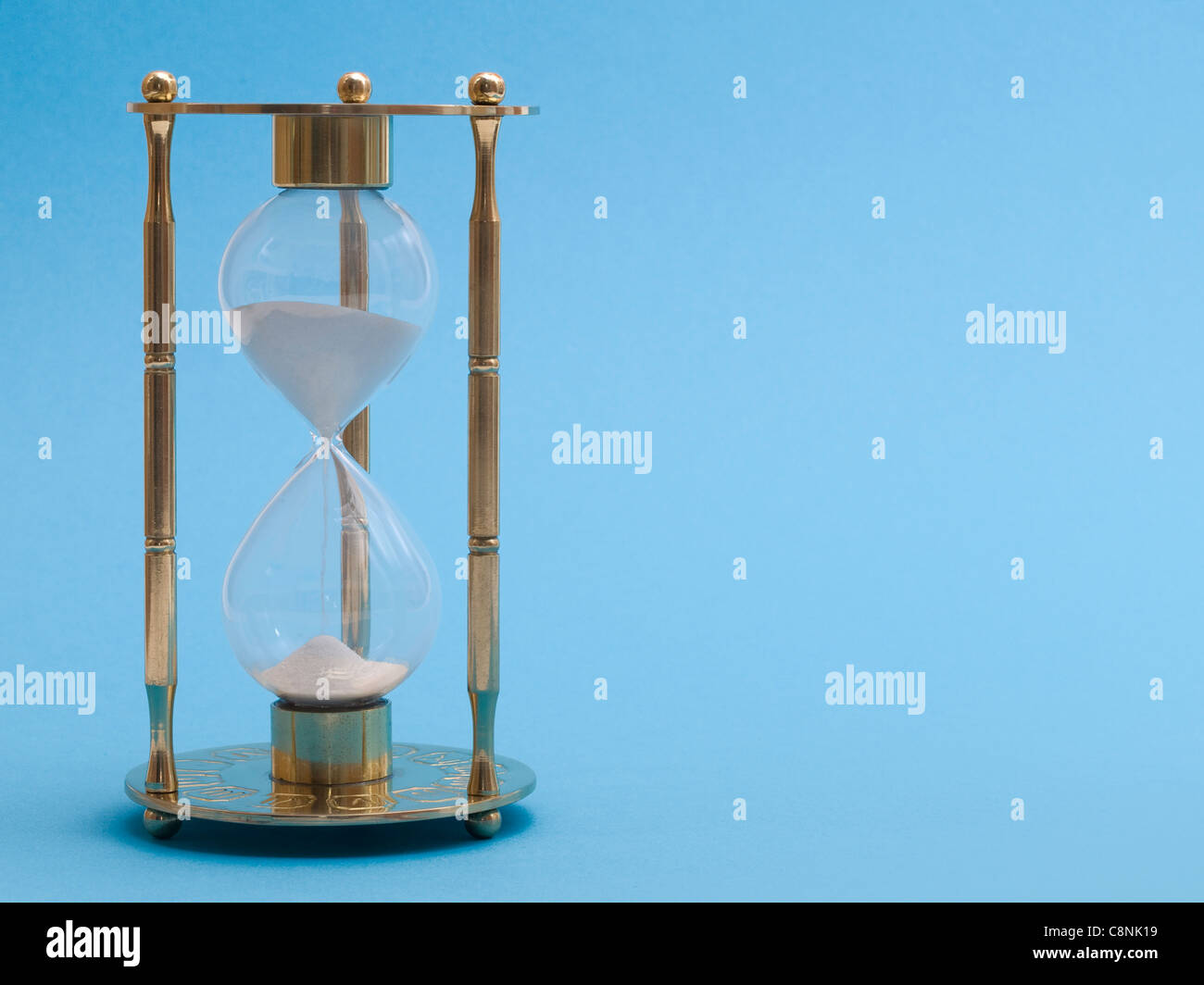 Detail photo of a golden sand glass in front of a blue background Stock Photo