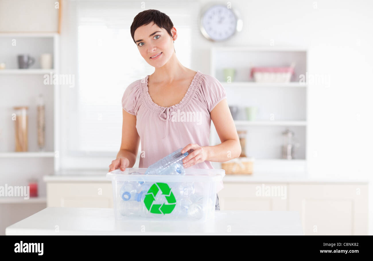 Smiling Woman putting bottles in a recycling box Stock Photo