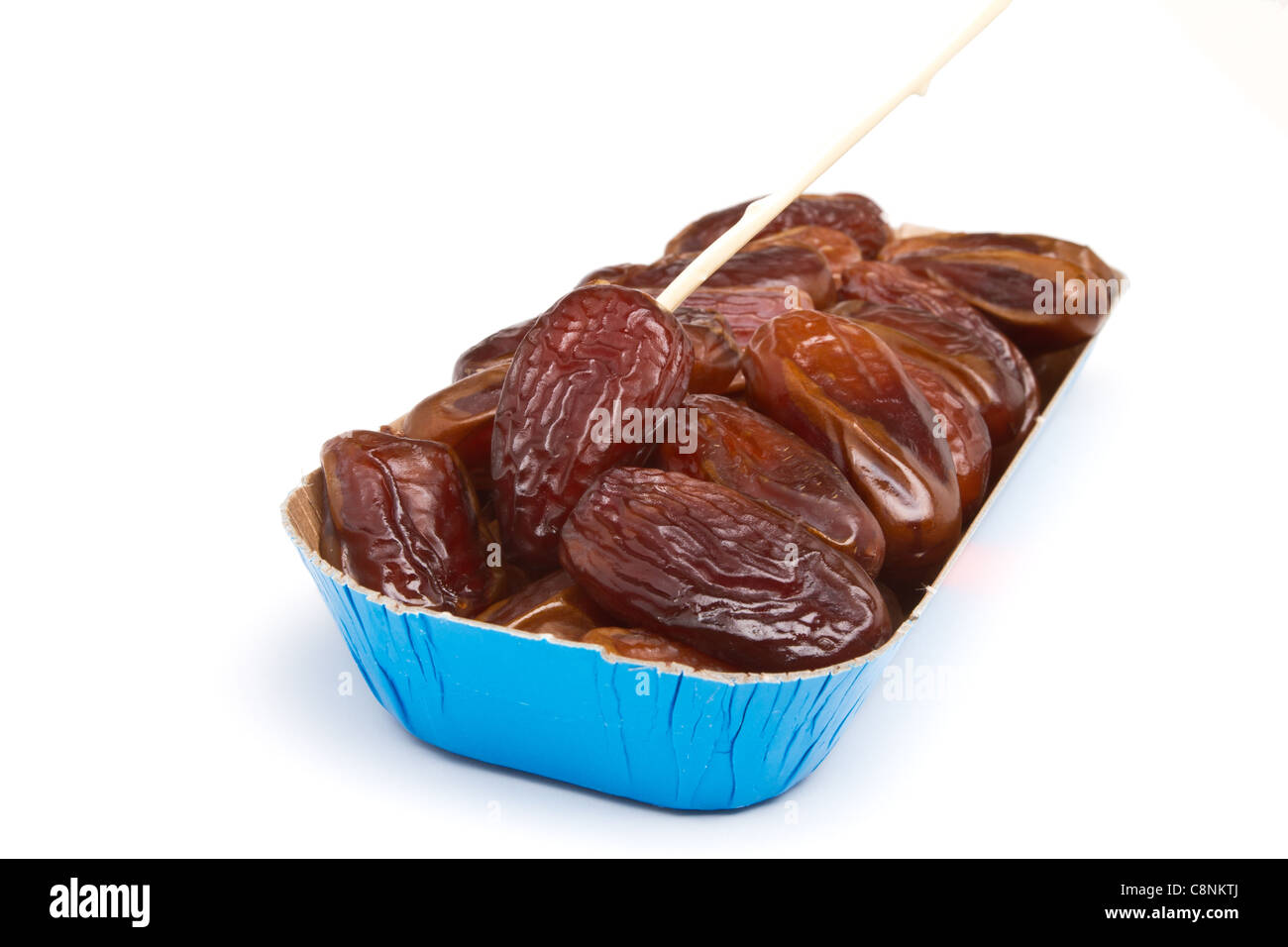 Cardboard tray of date fruits with skewer on white background. Stock Photo