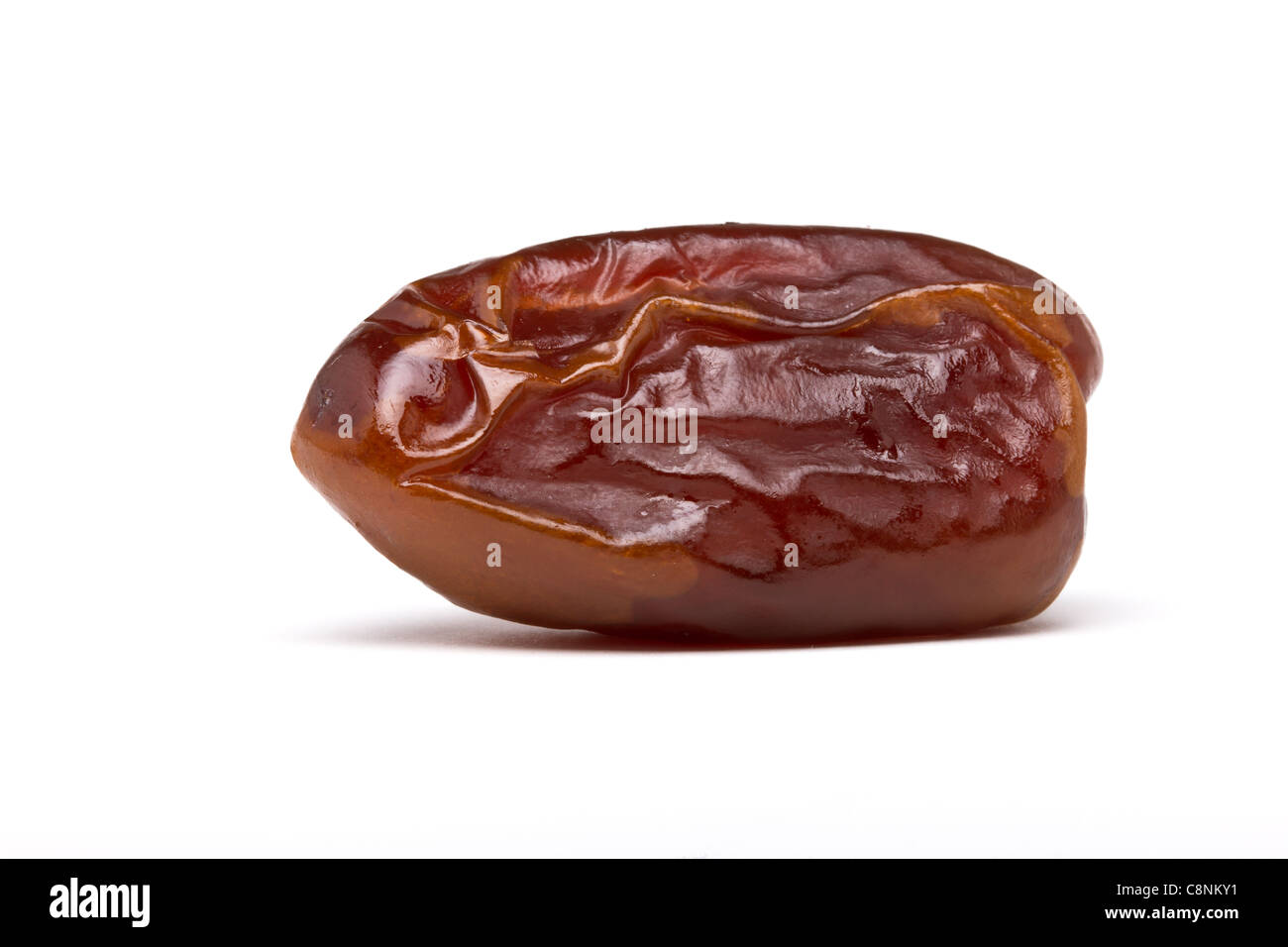 Single dried date fruit from low perspective on white background. Stock Photo