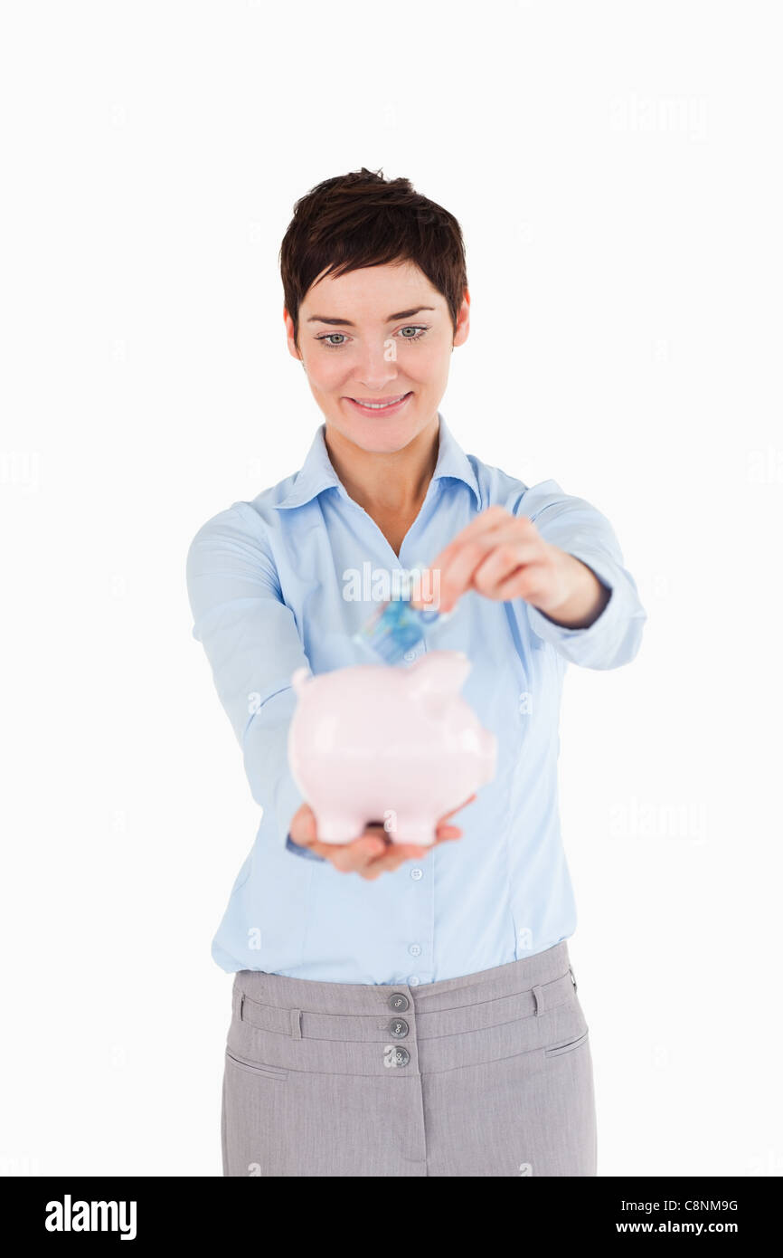 Woman putting a bank note in a piggy bank Stock Photo - Alamy