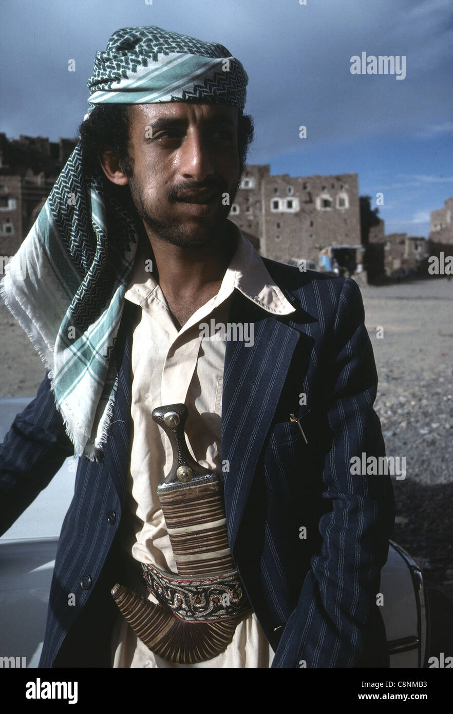 A Yemeni man wearing traditional dress with the djambia (dagger) in his belt. His cheek is holding qat. Stock Photo