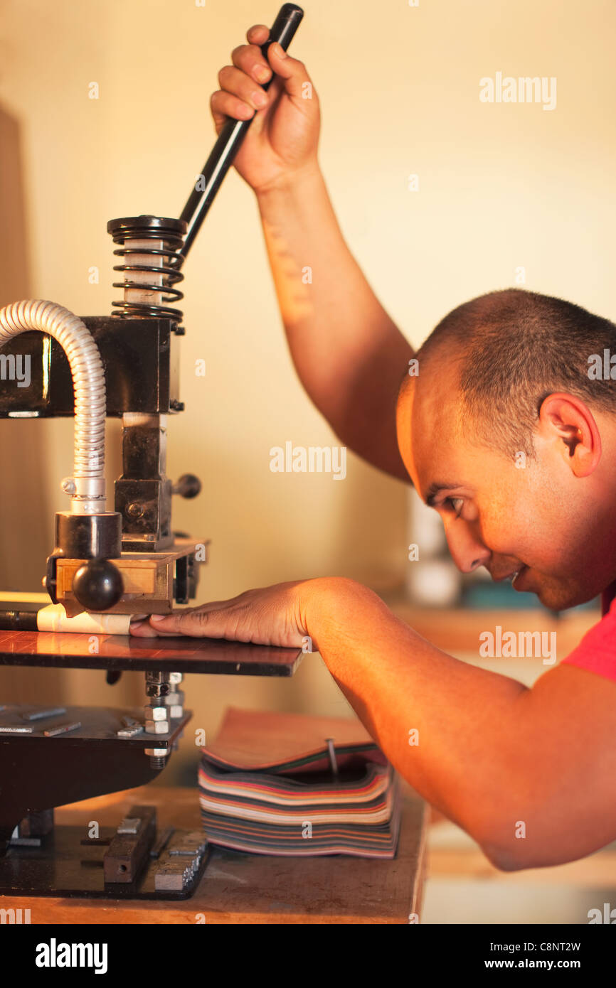 Hispanic man operating book-binding machine Stock Photo