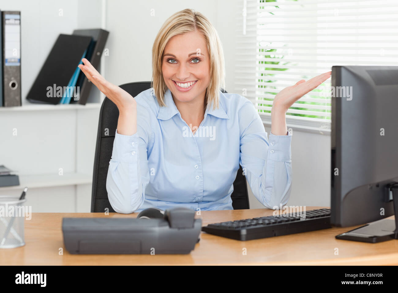 Smiling Blonde Woman Sitting Behind Desk Not Having A Clue What To