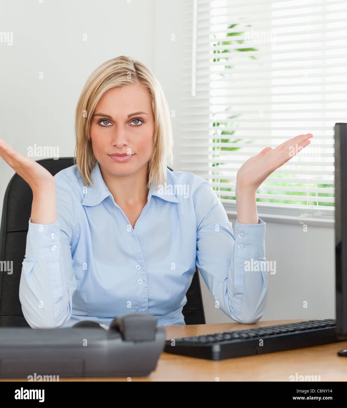 Serious Woman Sitting Behind Desk Not Having A Clue What To Do