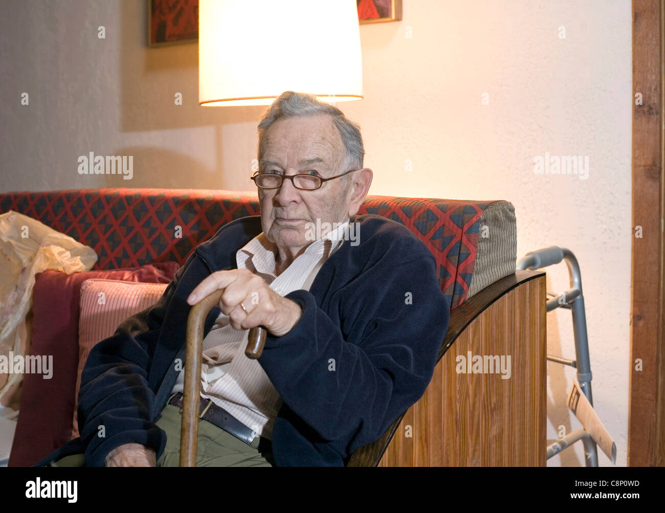 A senior man sitting and holding his cane. Stock Photo
