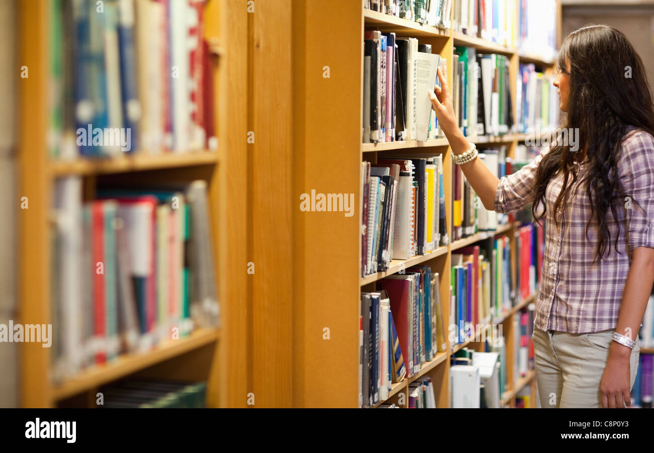 Около книг. Женщина в книжном магазине. Девушка выбирает книгу. Девушка выбирает книгу в библиотеке. Девушка около стеллажа с книгами.