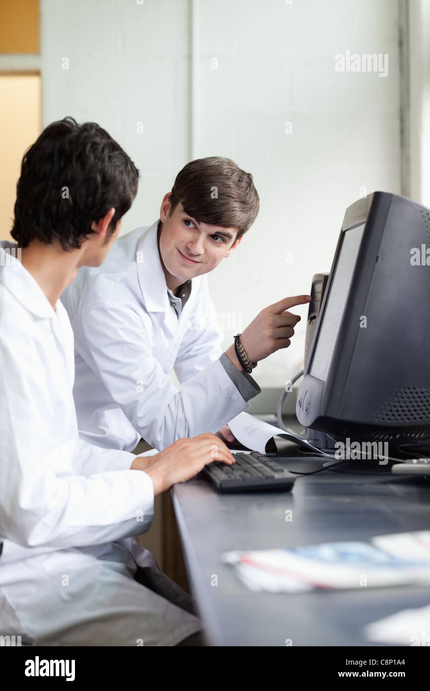 Scientist pointing at something on a monitor to his colleague Stock ...