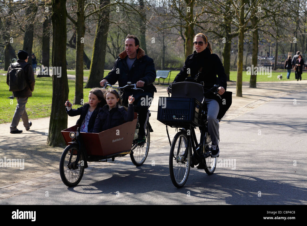 Family cycling in the Vondelpark with children in Bakfiets carrier bike Amsterdam Holland Netherlands Stock Photo