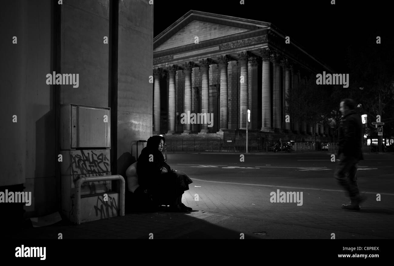 Urban poverty, Old Roma woman, address hidden behind trash cans Place de la Madeleine Paris Stock Photo