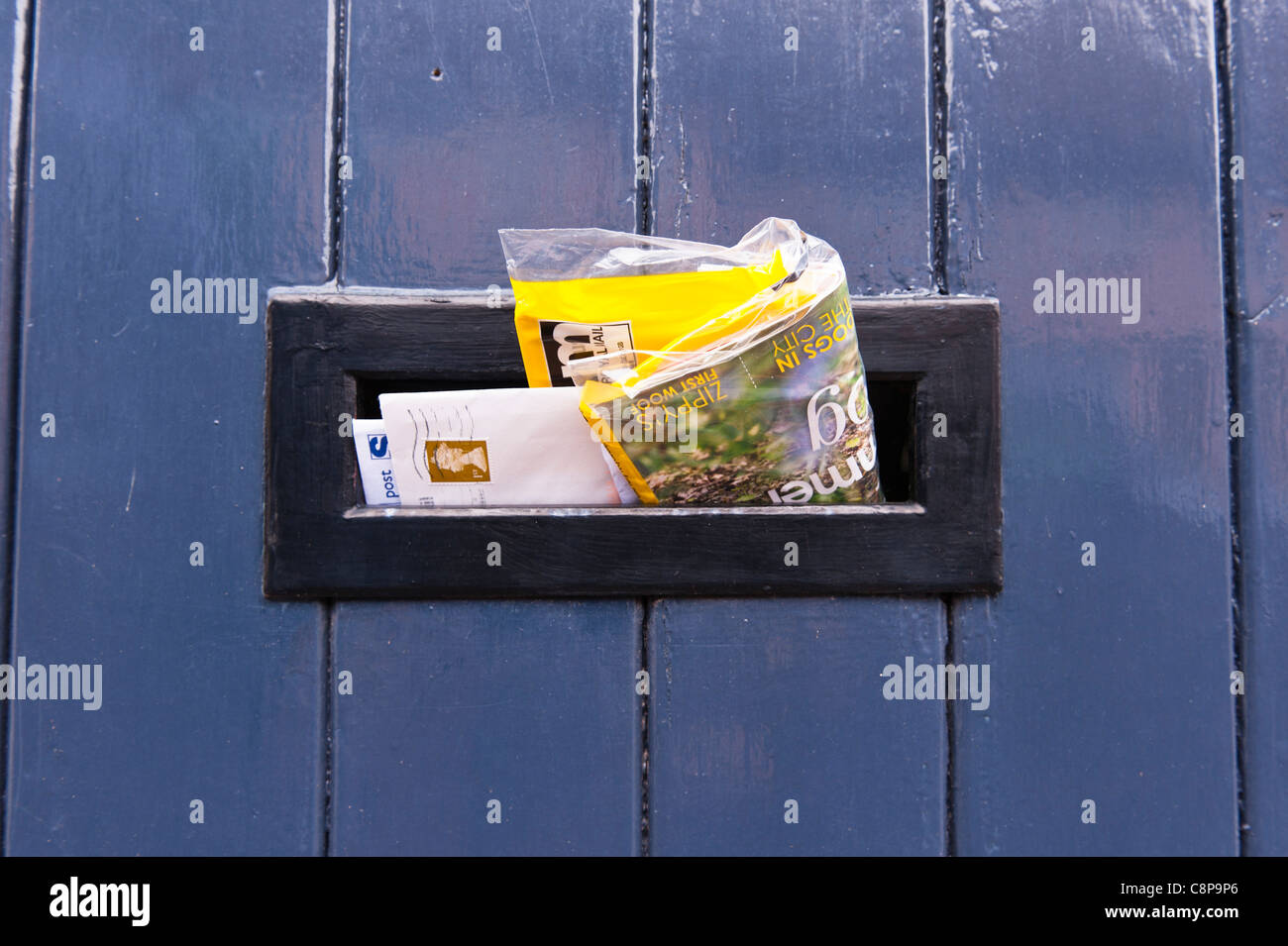 Letters and mail sticking out of a Uk letterbox in the front door of a house Stock Photo