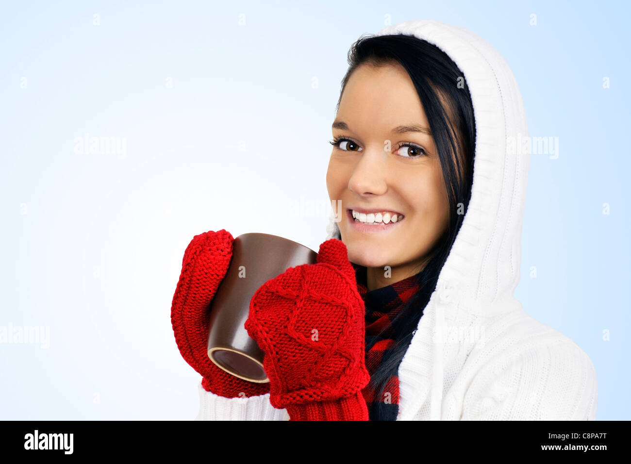 Beautiful young woman drinking hot beverage in coffee mug during cold