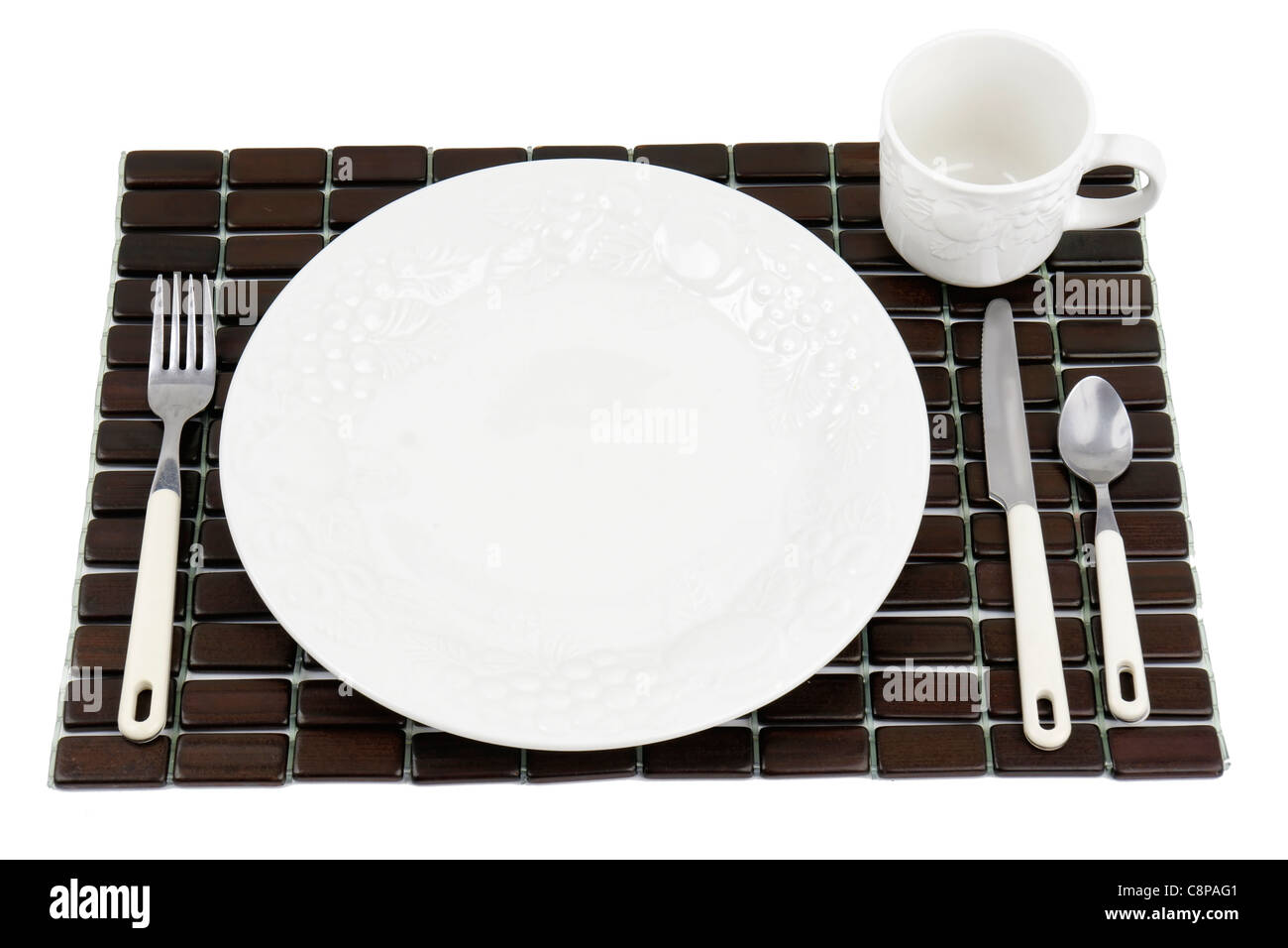 Dinner plate, white textured China with grapes and tomatoes design over a dark wood place mat. Stock Photo