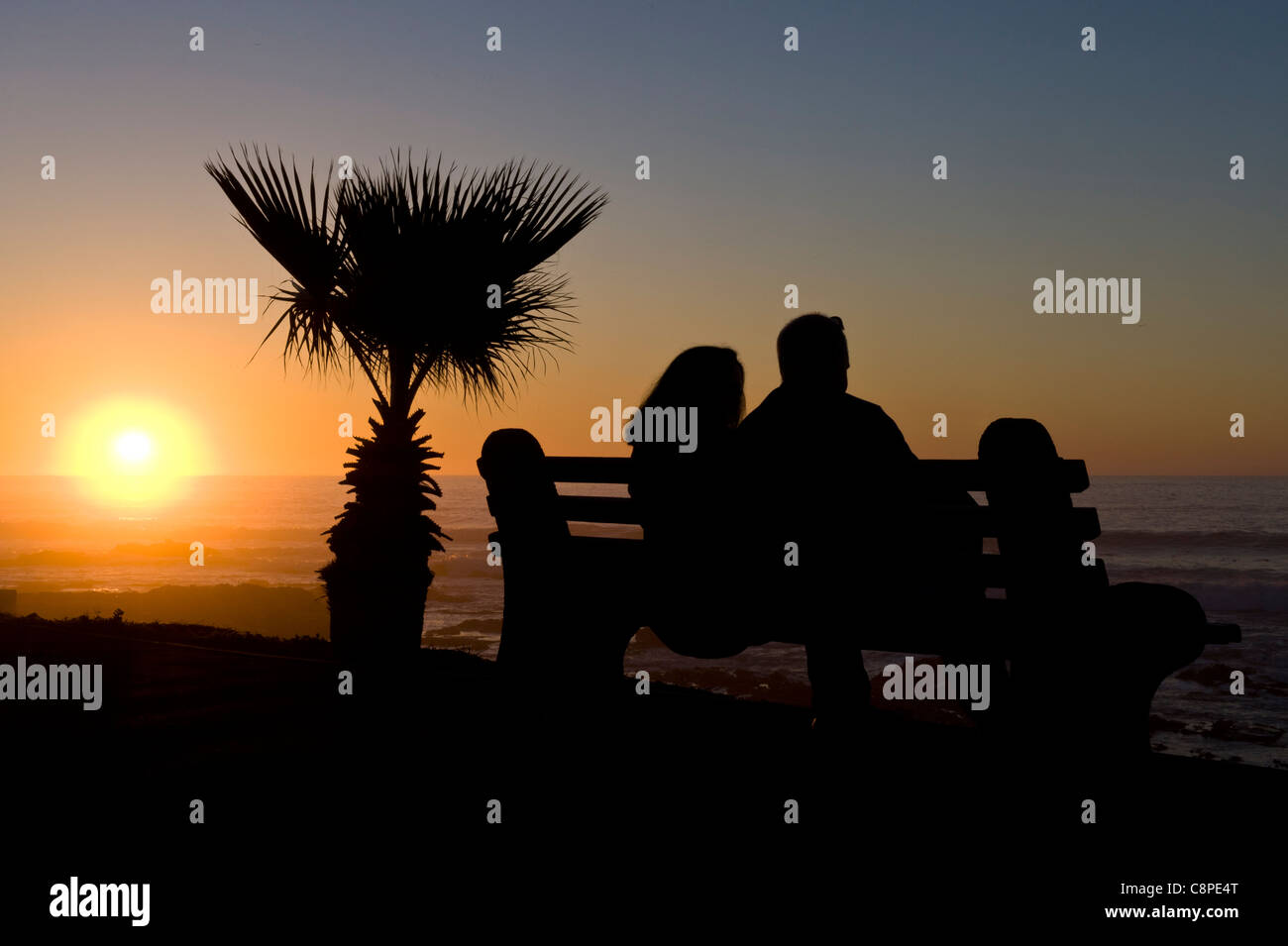 Couple watching the sunset over the Atlantic Ocean view from Mouille Point Cape Town South Africa Stock Photo