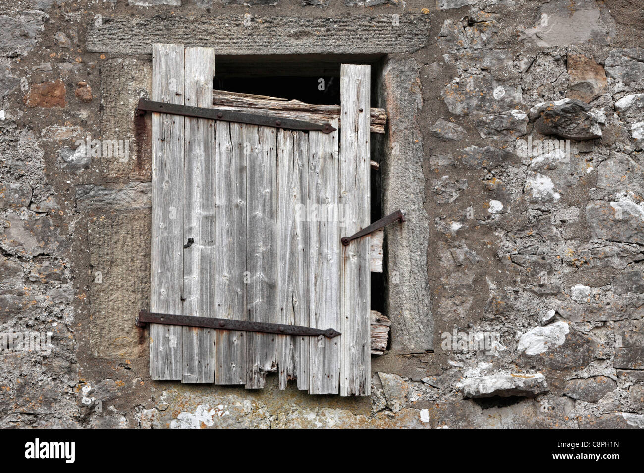 A wooden door hangs precariously from the top of a stone barn in the Yorkshire Dales of England Stock Photo
