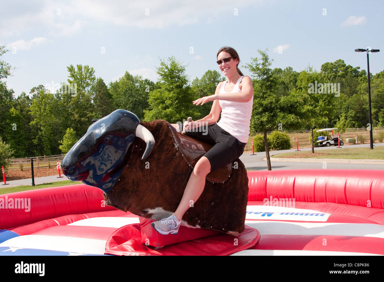 Woman riding a mechanical bull at a festival Stock Photo