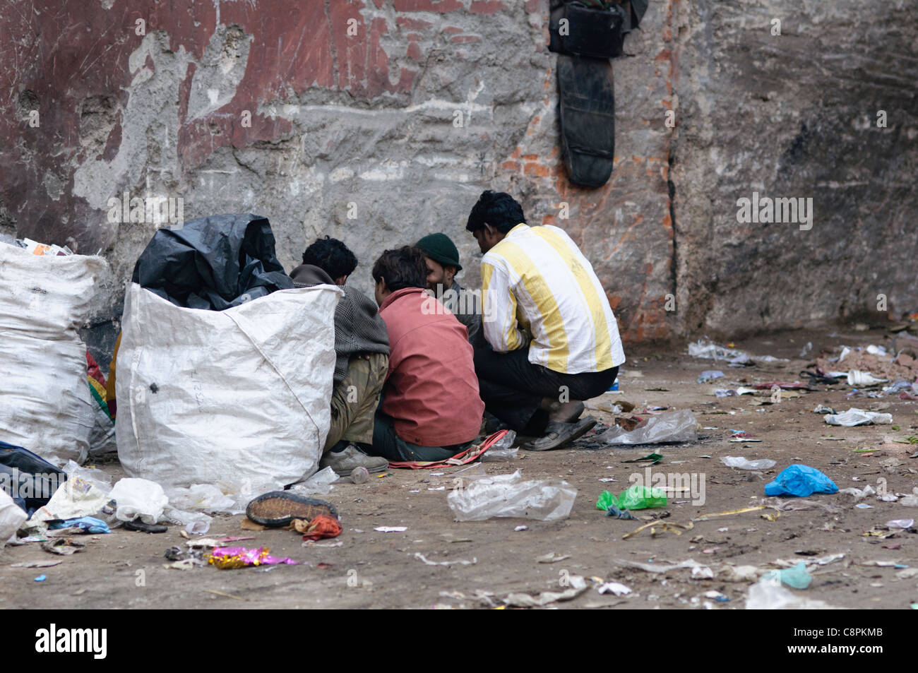 Men huddle around to smoke heroin in Delhi. Drug abuse in India is increasing, especially in large urban areas. Stock Photo