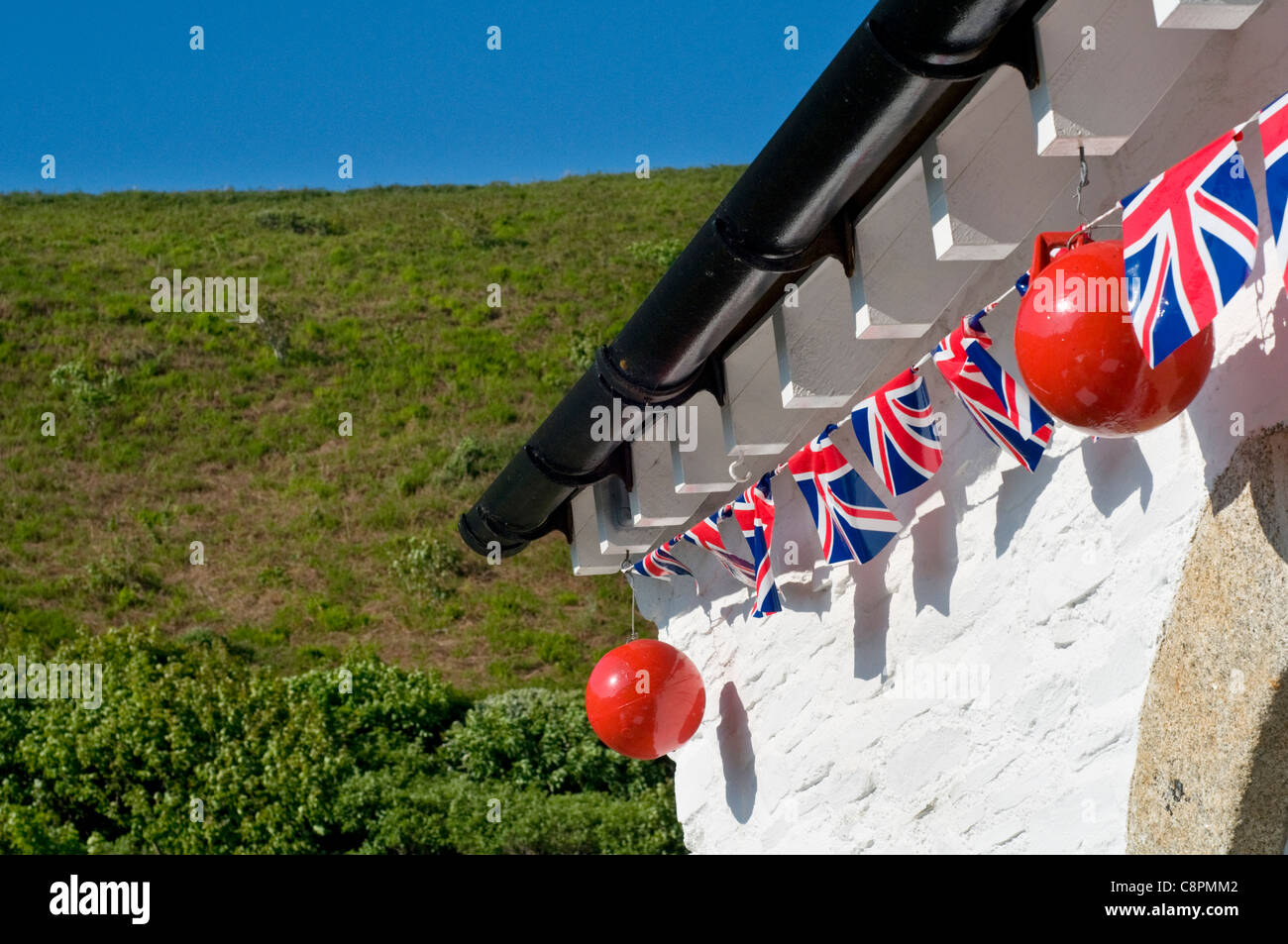 A string of Union Jack bunting on a white building in Cornwall, England