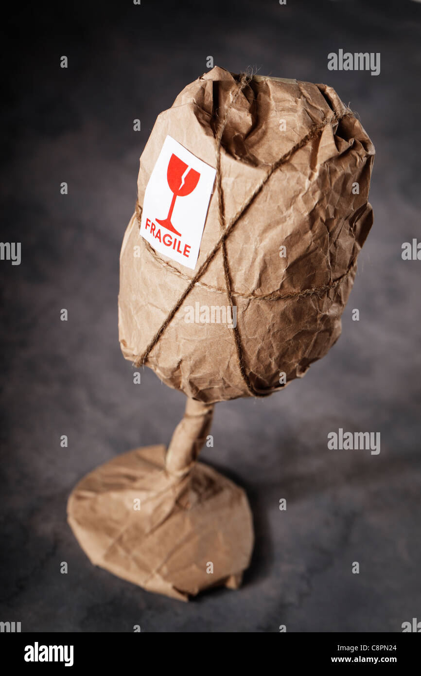 A Wine glass packaged in brown wrapping paper with 'Fragile' warning sticker. Stock Photo