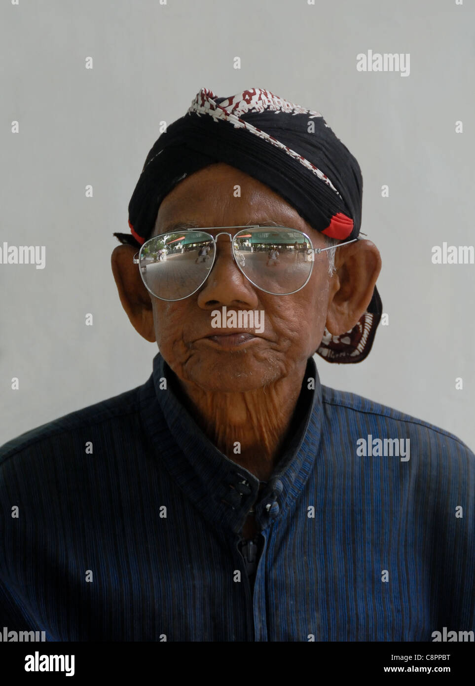 Portrait of one of the sultan of Yogjakarta's men. Sunglasses and against a gray background.  A distinguished old gentleman. Stock Photo