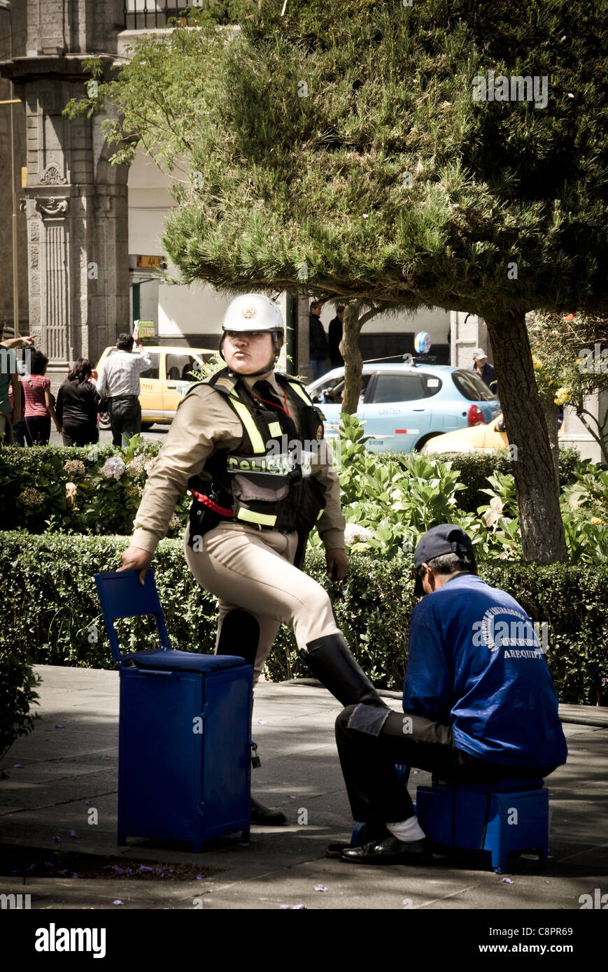 Police woman and street shoe shiner in Arequipa Peru Stock Photo