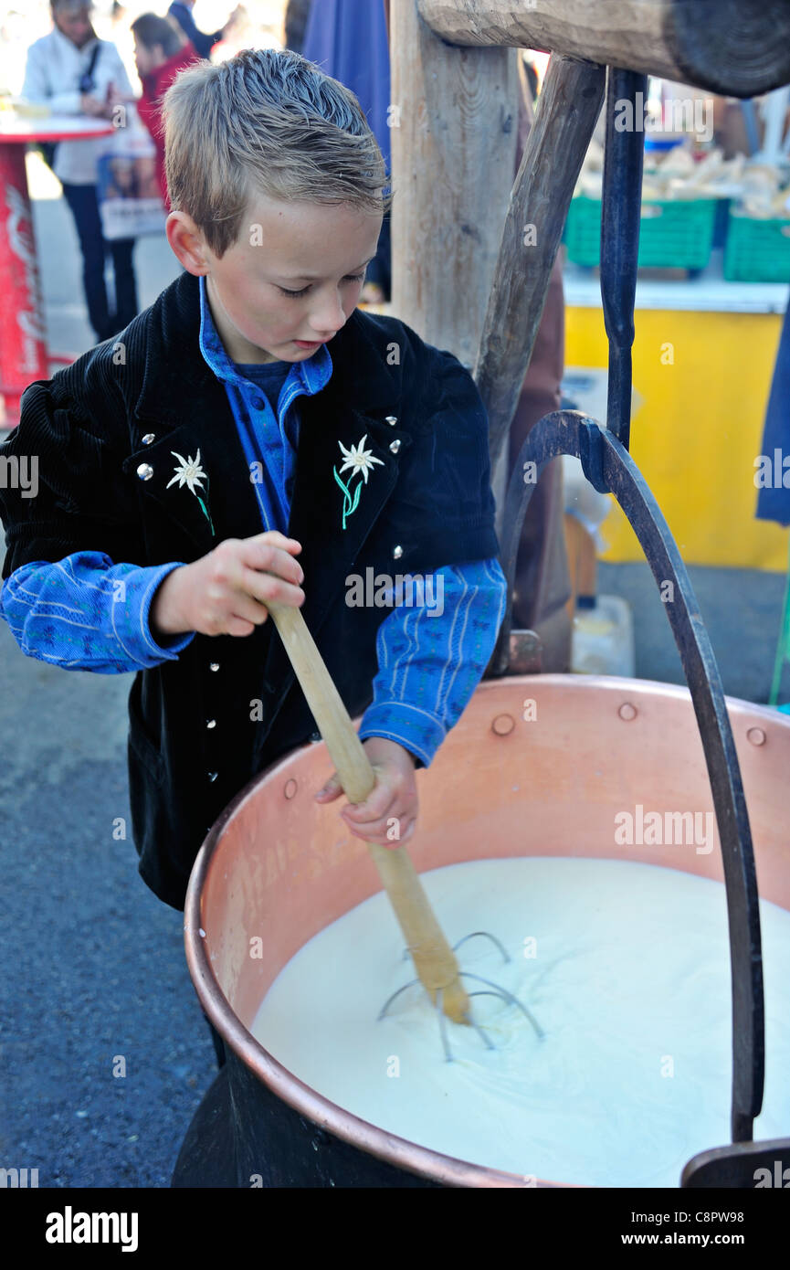A Swiss boy in traditional dress making cheese. Slight motion blur on