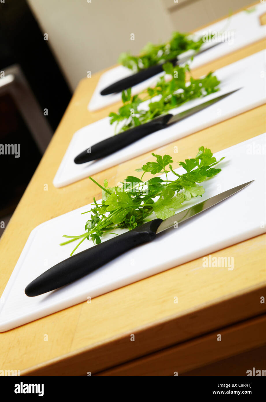 Green herbs on chopping board with kitchen knife. Ready for chopping in cookery class. Stock Photo