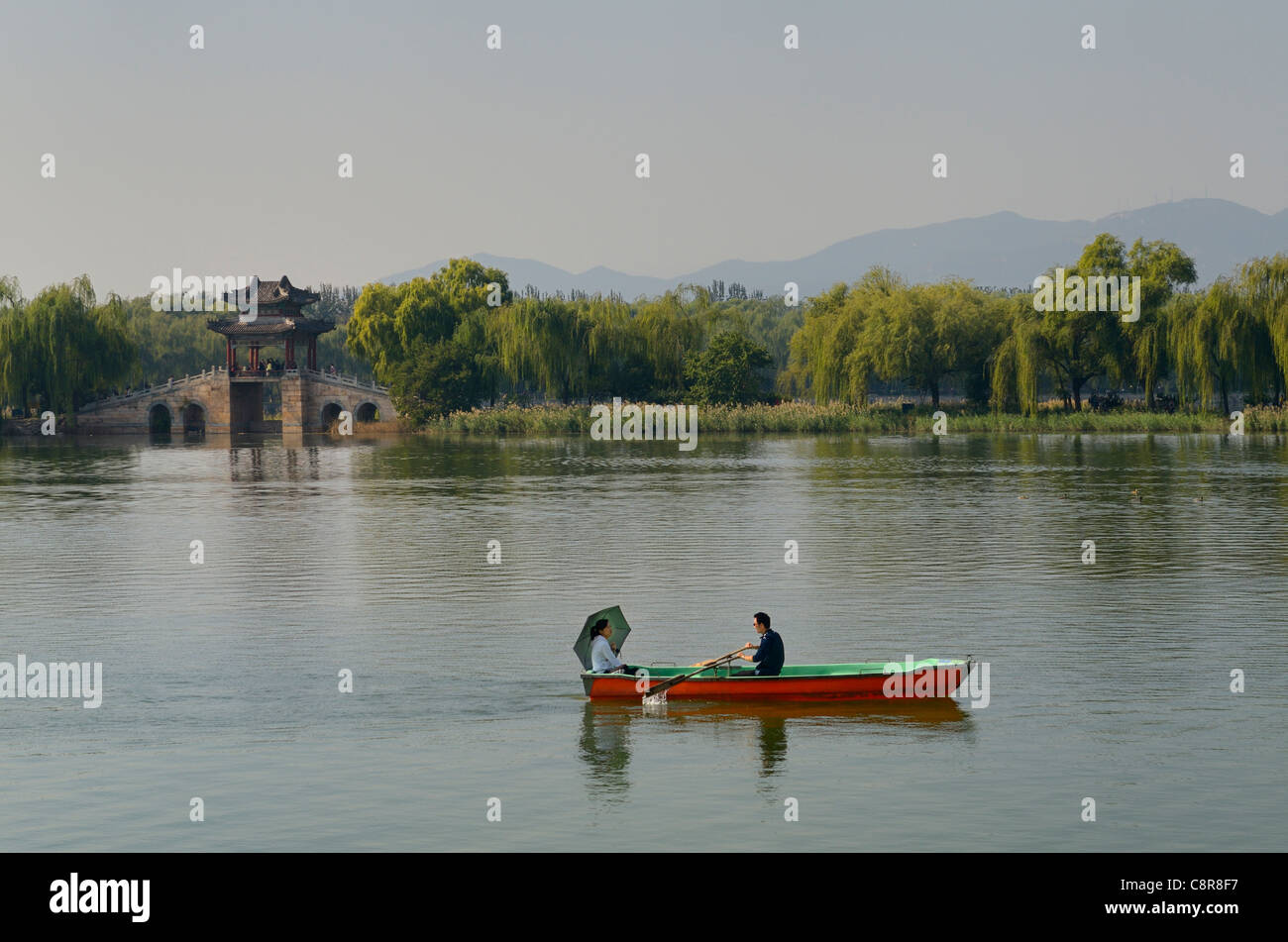 Couple rowing past the Willow Bridge on South Kunming Lake Summer Palace Beijing Peoples Republic of China Stock Photo