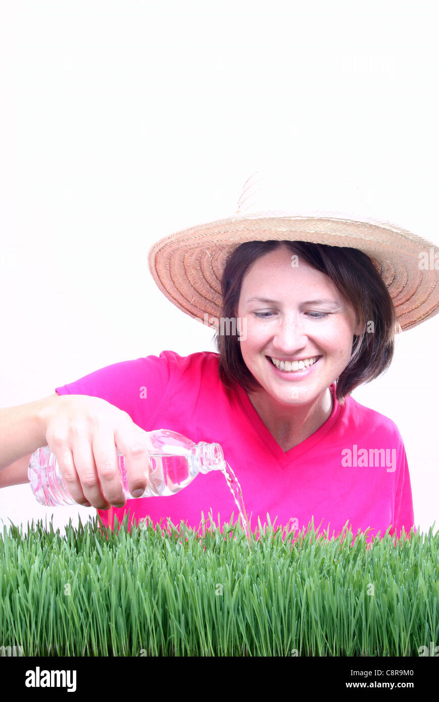 A woman pouring water on grass from a plastic bottle focus on water