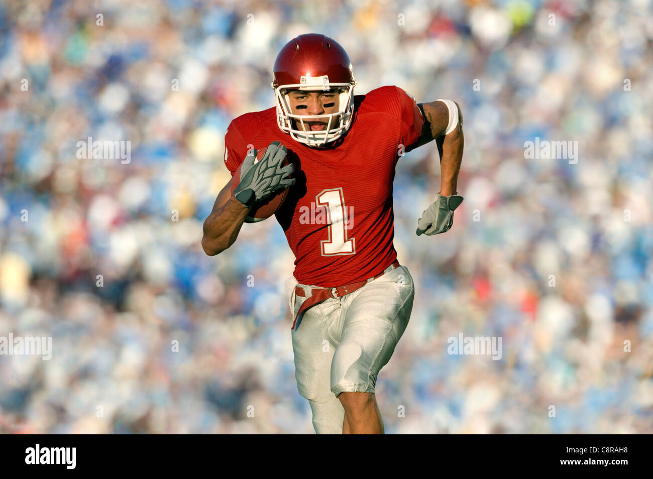 African American football player running on field in game Stock Photo