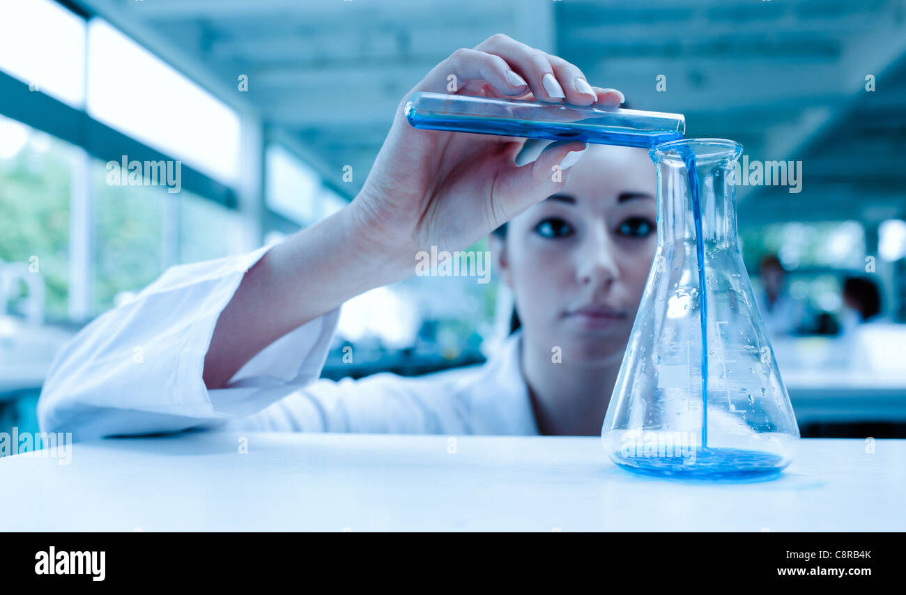 Scientist pouring a liquid in an Erlenmeyer flask with a test tube