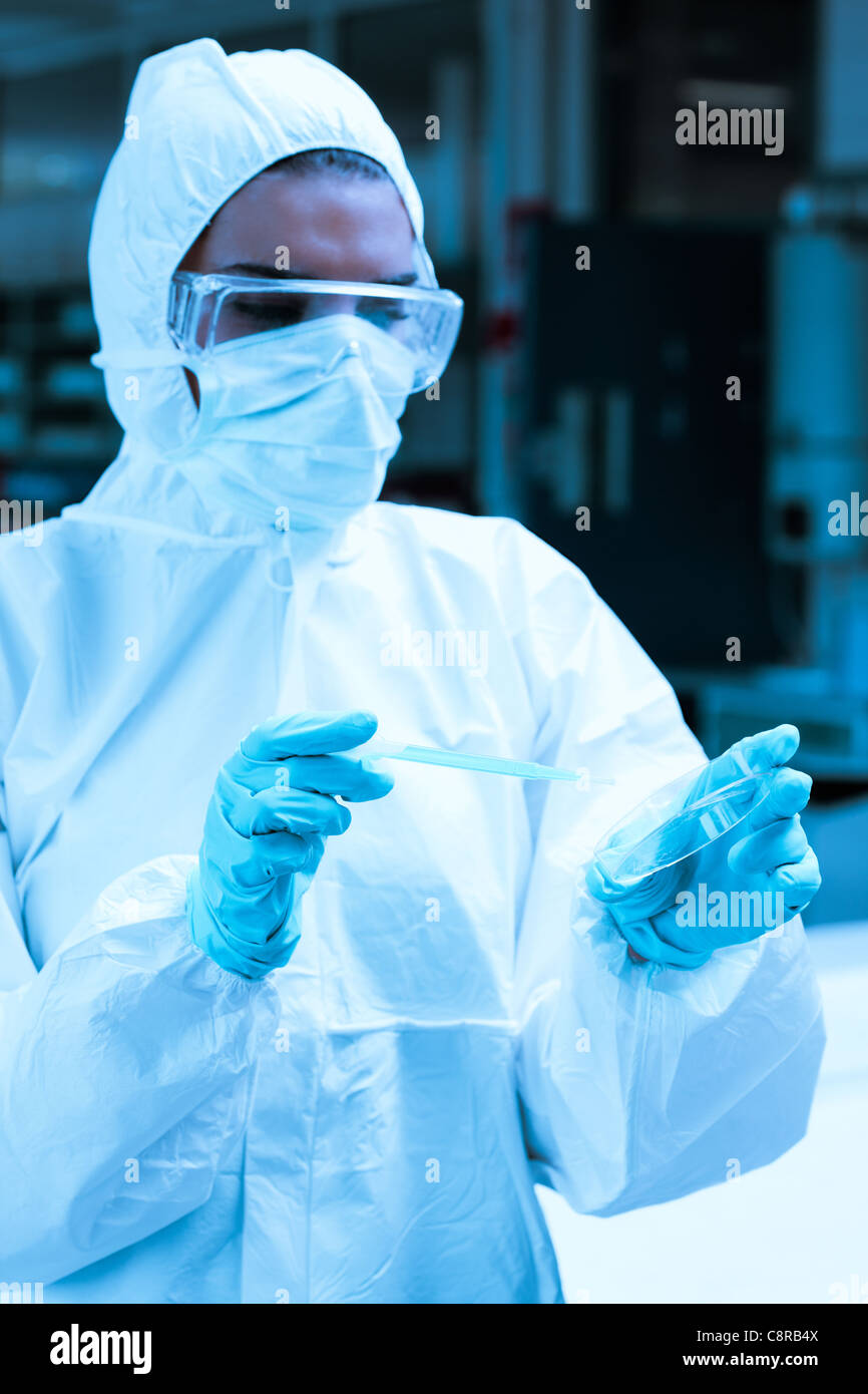 Protected scientist dropping dangerous liquid in a Petri dish Stock Photo