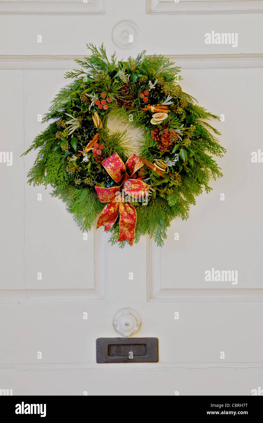 A traditional Christmas wreath hangs upon a white door Stock Photo
