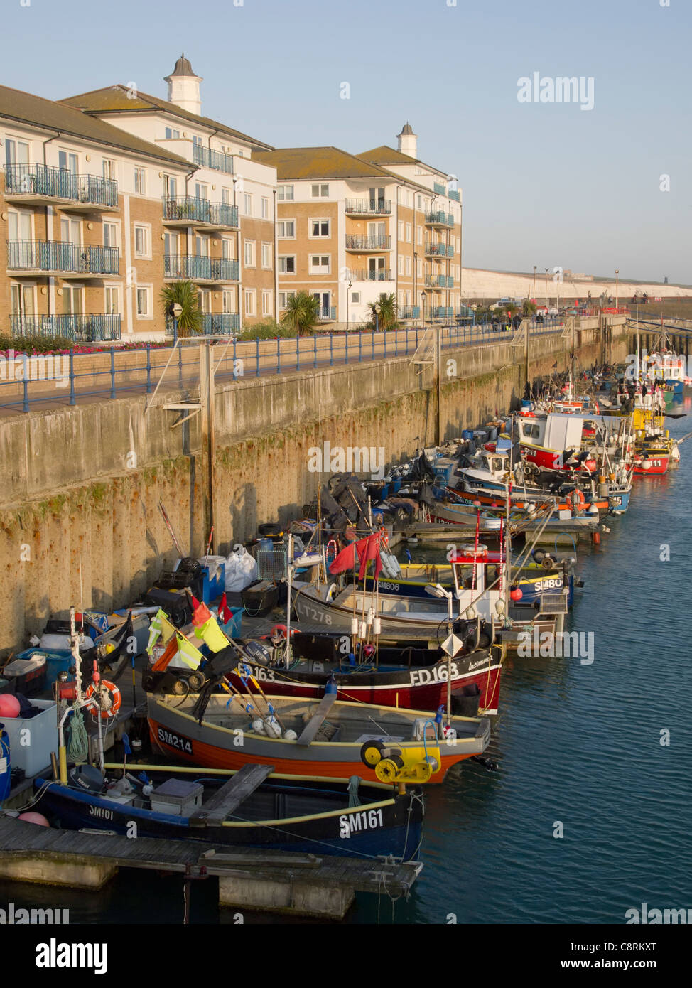 Fishing boats moored alongside residential homes in Brighton Marina, England. Stock Photo