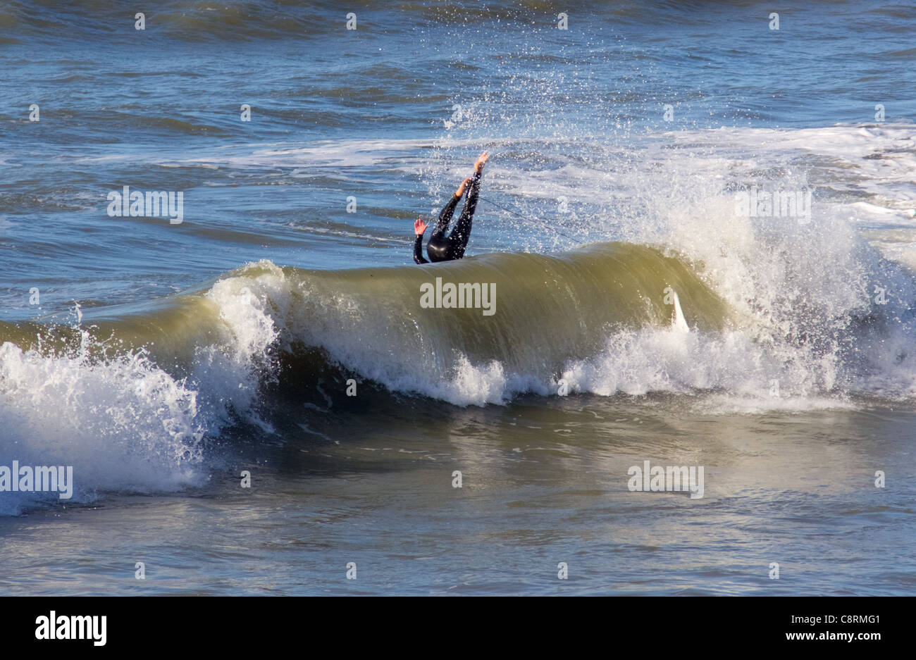 A surfer tumbles headlong into the waves while surfing in Cardigan Bay Stock Photo