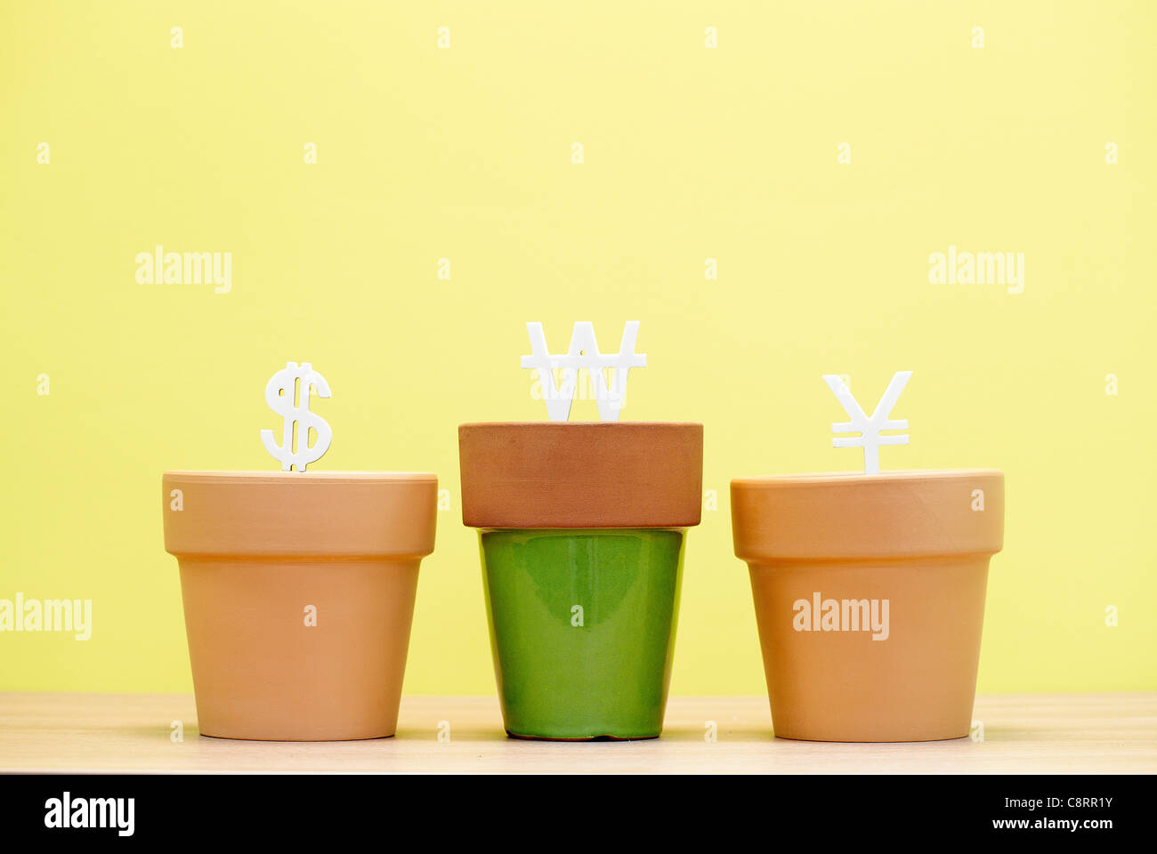 Three plant pots containing three different currency symbol Stock Photo