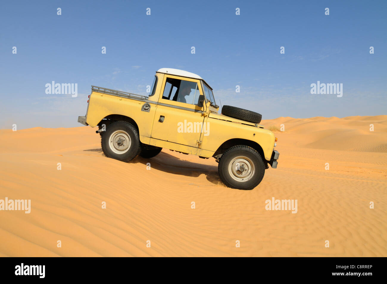 Africa, Tunisia, nr. Tembaine. Desert traveller driving his 1964 Land Rover Series 2a Truck Cab through a sandfield close to ... Stock Photo