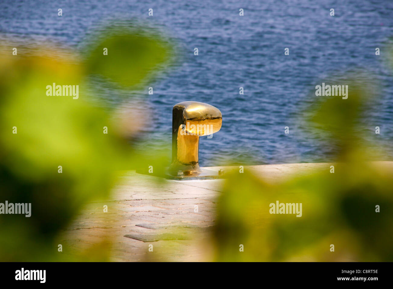 Gold coloured tie up bollard on harbourside jetty Stock Photo