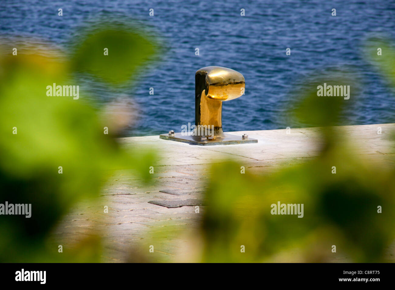 Gold coloured tie up bollard on harbourside jetty Stock Photo