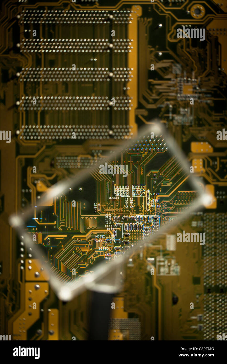 Looking at circuit board through magnifying glass Stock Photo - Alamy
